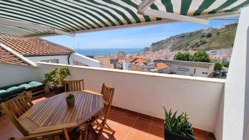 a patio with a table and chairs on a balcony at Casa Avô Nino in Nazaré