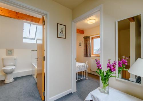 a bathroom with a toilet and a vase of purple flowers at Brights Farm Lodge in Bramfield