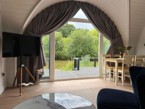 a living room with a large window and a tv at Nestledstays- The Lake House in Arundel