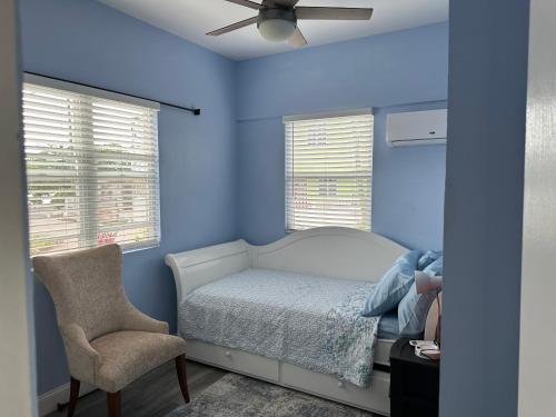 1 dormitorio con paredes azules, 1 cama y 1 silla en Lucia Bayview House en Glanvillia