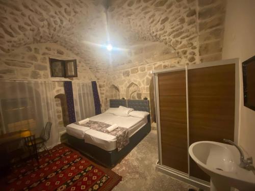 1 dormitorio con 1 cama y lavamanos en un edificio en Gılgamesh butik otel en Mardin
