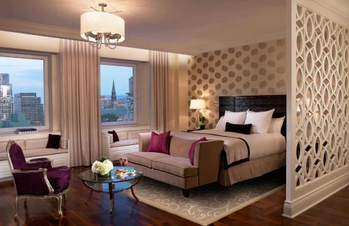 een slaapkamer met een bed, een bank en een raam bij The Ritz-Carlton, Montreal in Montreal