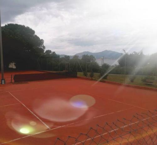 um campo de ténis com uma raquete de ténis em Porticcio avec Piscine proche plage em Porticcio