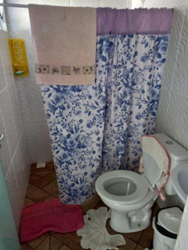 a bathroom with a toilet and a blue and white shower curtain at Casa temporada próximo à parque in Penha