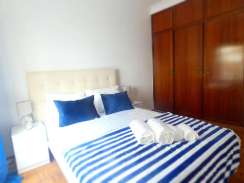 Schlafzimmer mit einem großen Bett mit blauer und weißer Bettwäsche in der Unterkunft Apartamento Marisol Confort in Aroeira