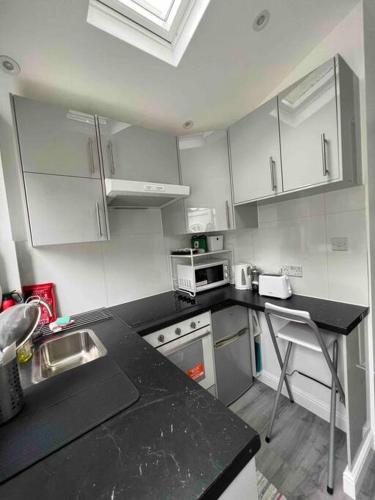 a kitchen with white cabinets and a black counter top at Studio apartment/flat in Chislehurst
