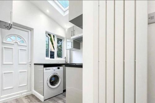 a white kitchen with a washing machine and a door at Studio apartment/flat in Chislehurst