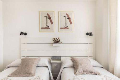 a bedroom with two beds and two pictures on the wall at Piso climatizado y parking in Madrid