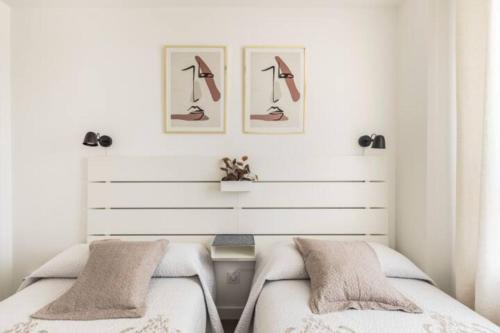 een slaapkamer met twee bedden en twee foto's aan de muur bij Piso climatizado y parking in Madrid