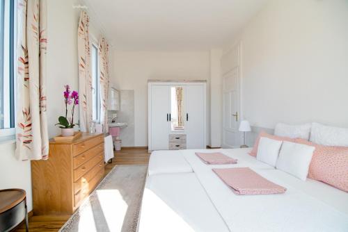 a white bedroom with a large bed and a dresser at Pensione Solaria in Locarno