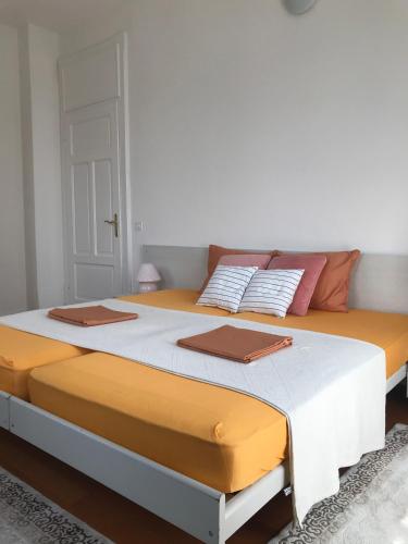a large bed with orange and white sheets and pillows at Pensione Solaria in Locarno