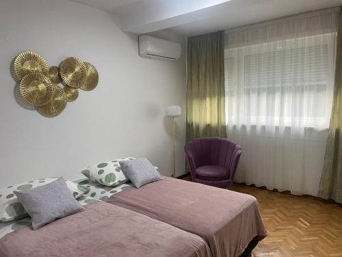 a bedroom with a bed and a purple chair at Apartman Doris in Split