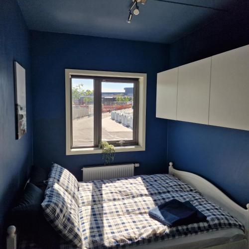 Dormitorio azul con cama y ventana en Spacious 1 bedroom apartment en Lorenskog