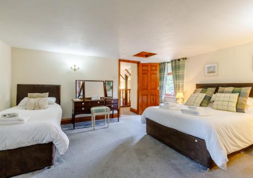 1 dormitorio con 2 camas, escritorio y espejo en Ash Cottage en Dulverton