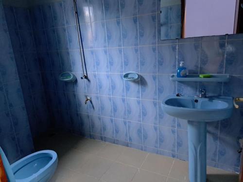 baño de azulejos azules con lavabo y aseo en illémi Guest house, en Abomey-Calavi