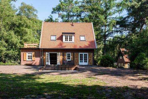 een klein huis met een rood dak op een erf bij Fantastisch familiehuis met grote tuin I Bosrijk in Lunteren