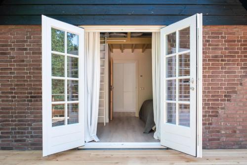 an open door leading to a brick house with a door at Fantastisch familiehuis met grote tuin I Bosrijk in Lunteren