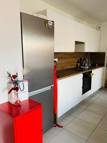 La cuisine est équipée d'un réfrigérateur rouge et de placards blancs. dans l'établissement Chambre cosy privée Villeurbanne proximité centre ville place de parking privée selon disponibilité, à Villeurbanne