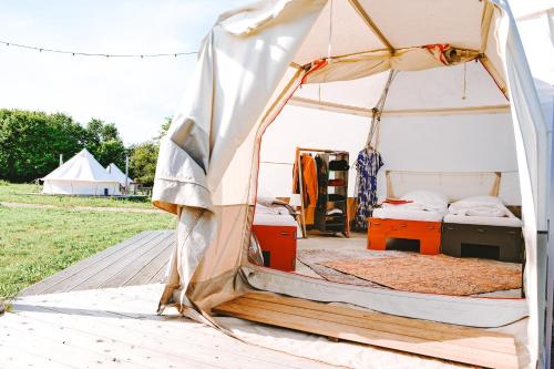 a tent with beds and chests in a field at DOMO CAMP - Nature Glamping Hof Viehbrook in Rendswühren