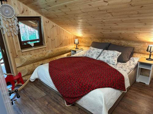 Un dormitorio con una cama en una cabaña de troncos en Wikno Villa, en Nidzica