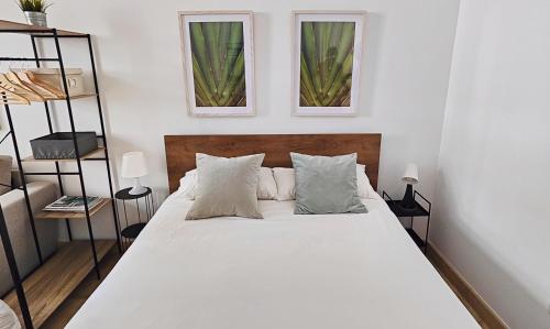 a bedroom with a large white bed with two windows at ESTUDIO TRANQUILO EN PLENO CENTRO DE MALAGA in Málaga