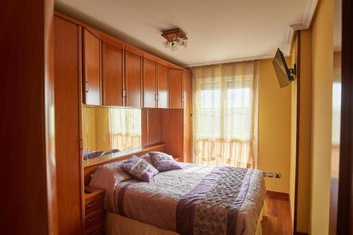 1 dormitorio con cama, armarios de madera y ventana en CAMINODEHEROS en Avilés