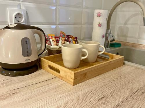 a coffee maker and two coffee cups on a cutting board at Airport Alexandra Apartments in Surčin