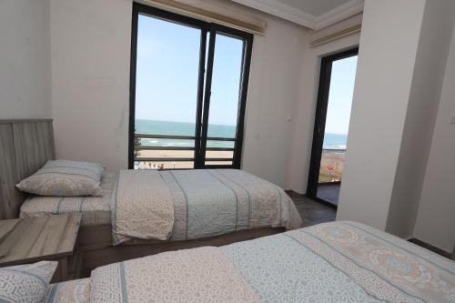 two beds in a room with a view of the ocean at RÜYA PANSİYON APART OTEL in Yukarı Kocaali