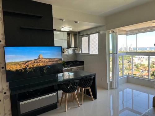 a kitchen with a large flat screen tv on the wall at Apartamento Horizonte Azul, vista lago, próximo ao shopping in Palmas