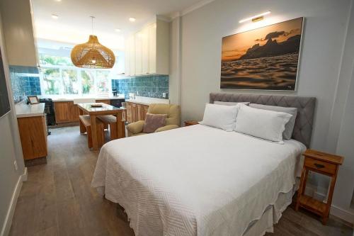 a bedroom with a white bed and a kitchen at Loft moderno no Alto-Leblon in Rio de Janeiro