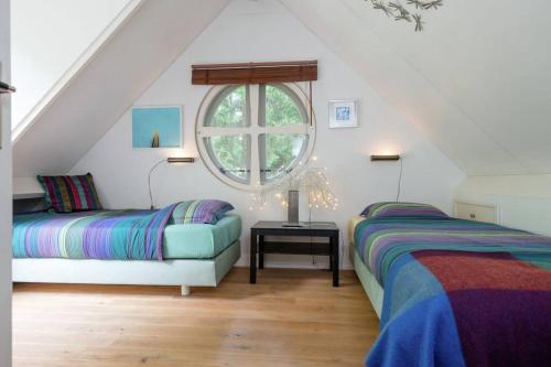 a attic room with two beds and a window at Het Boshuis in Dalfsen