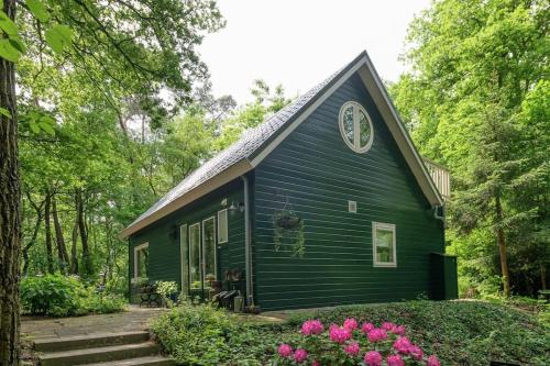 a green house with a clock on the side of it at Het Boshuis in Dalfsen