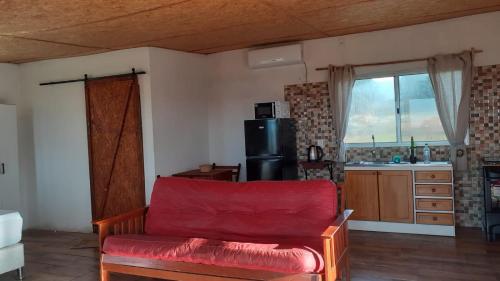 a living room with a red couch and a kitchen at Las Carobas in Minas