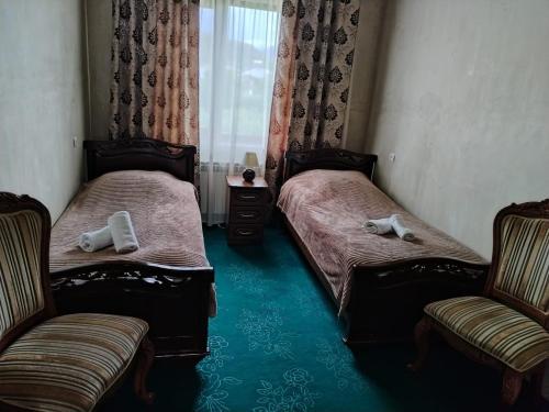 two beds in a room with two chairs and a window at Garni Guesthouse in Garni