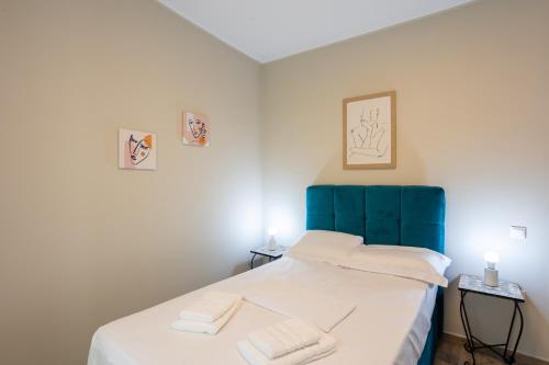 a bedroom with a bed with a blue headboard and two towels at Luxury & Cozy apartment in Messini