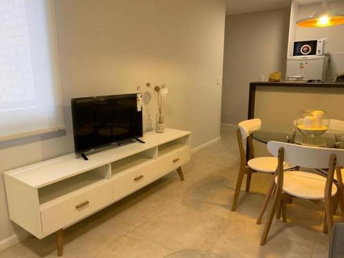 a living room with a tv and a table with chairs at Departamento Bv Illia By Lugar D276 in Cordoba