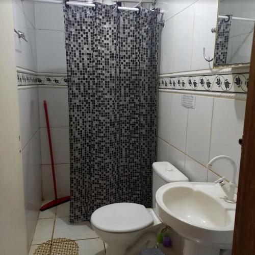 y baño con cortina de ducha, aseo y lavamanos. en Pousada Anhanguera, en Ribeirão Preto