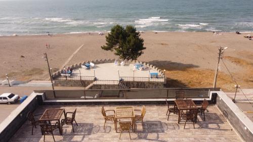 een groep tafels en stoelen naast een strand bij RÜYA PANSİYON APART OTEL in Yukarı Kocaali
