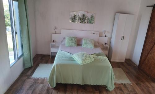 Schlafzimmer mit einem Bett mit grüner Bettwäsche und Kissen in der Unterkunft Las Carobas in Minas