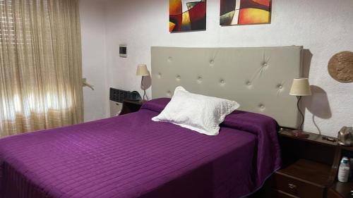 a purple bed with a white pillow on top of it at Casa con jardín, pileta, asador, y vistas al lago en Embalsina in Villa del Dique