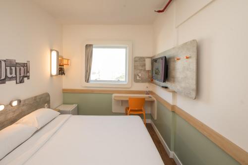 a small room with a bed and a tv at ibis budget Campinas Aquidaban in Campinas