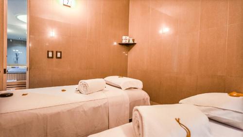 two beds in a room with white towels on them at Suites Inn la Muralla Hotel & Spa in Toluca