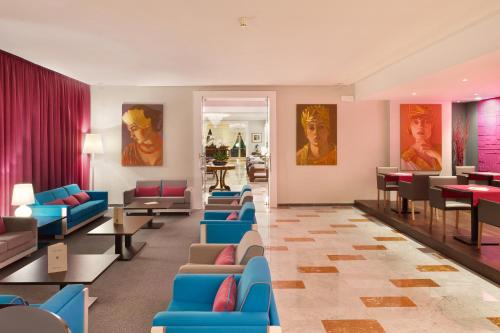 a waiting room with blue chairs and tables and paintings at Hotel Continental in Sorrento