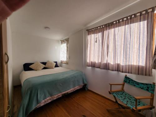 a bedroom with a bed and a chair and a window at La serena in San Carlos de Bariloche