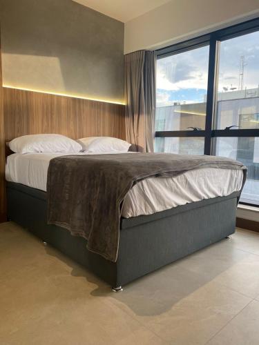 a bed in a bedroom with a large window at Apartamento novo de alto padrão e aconchegante#224 in Brasilia