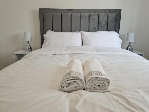 two towels on a white bed with two lamps at Serenity Space Luxury Home 3 Bed House Near Bluewater in Kent