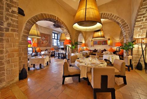 a restaurant with tables and chairs in a room with arches at Madada Mogador in Essaouira