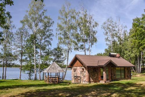 a small cabin with a gazebo next to a lake at Duriu sodyba in Molėtai