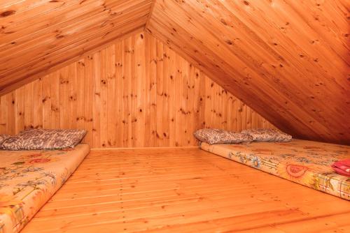 two beds in a room with wood paneling at Duriu sodyba in Molėtai