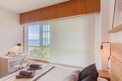 ein Wohnzimmer mit einem großen Fenster und einem Sofa in der Unterkunft San Amaro Beach 1 by TheBlueWaveApartments com in A Coruña